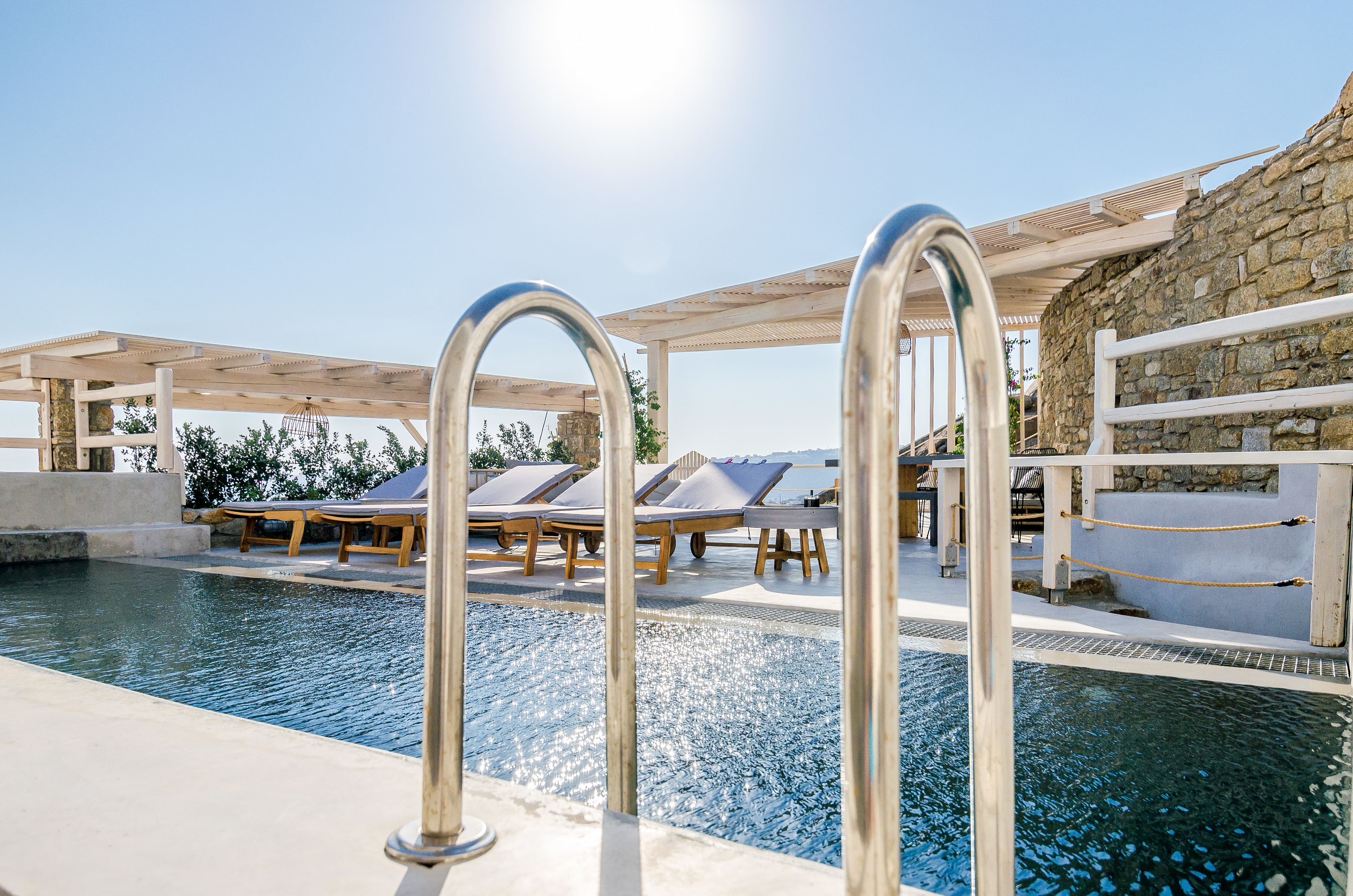A pool area with lounge chairs and a pergola.