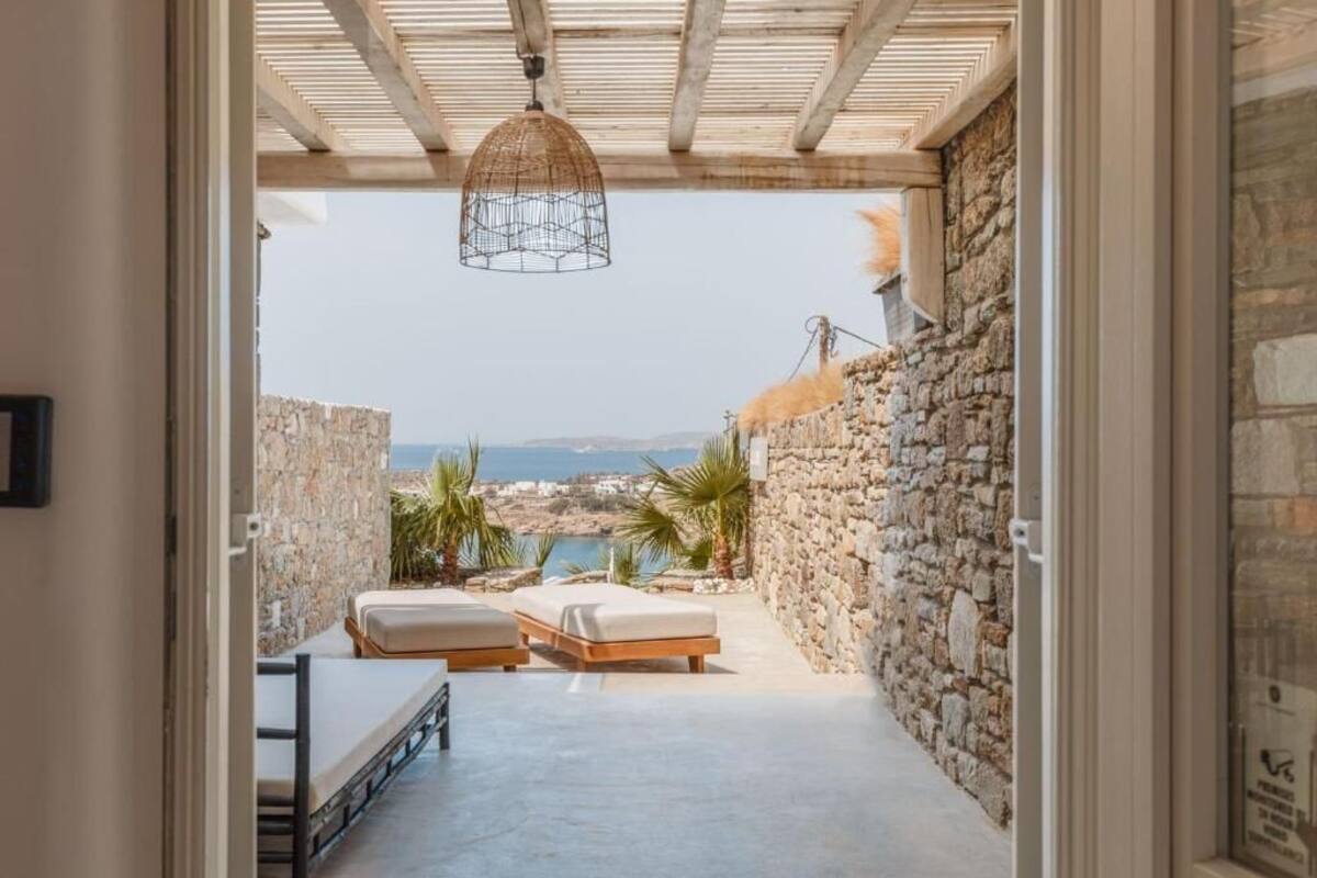 A narrow corridor with a stone wall, a bed, a bench, and a hanging light fixture.