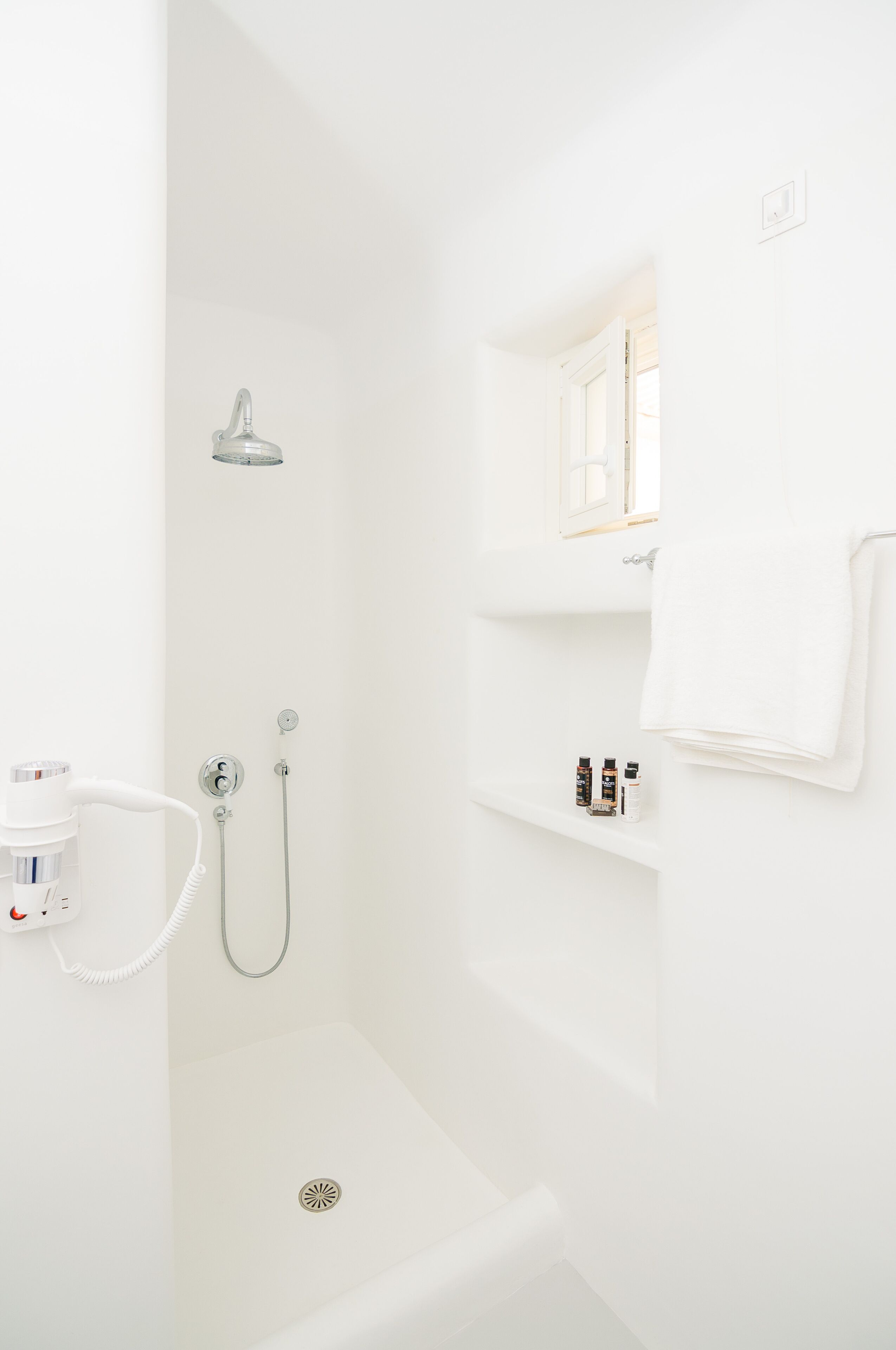 Une salle de bain blanche avec une douche, un lavabo et un miroir.