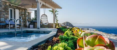 Ein Poolbereich mit Pergola, Sitzgelegenheiten und Meerblick.