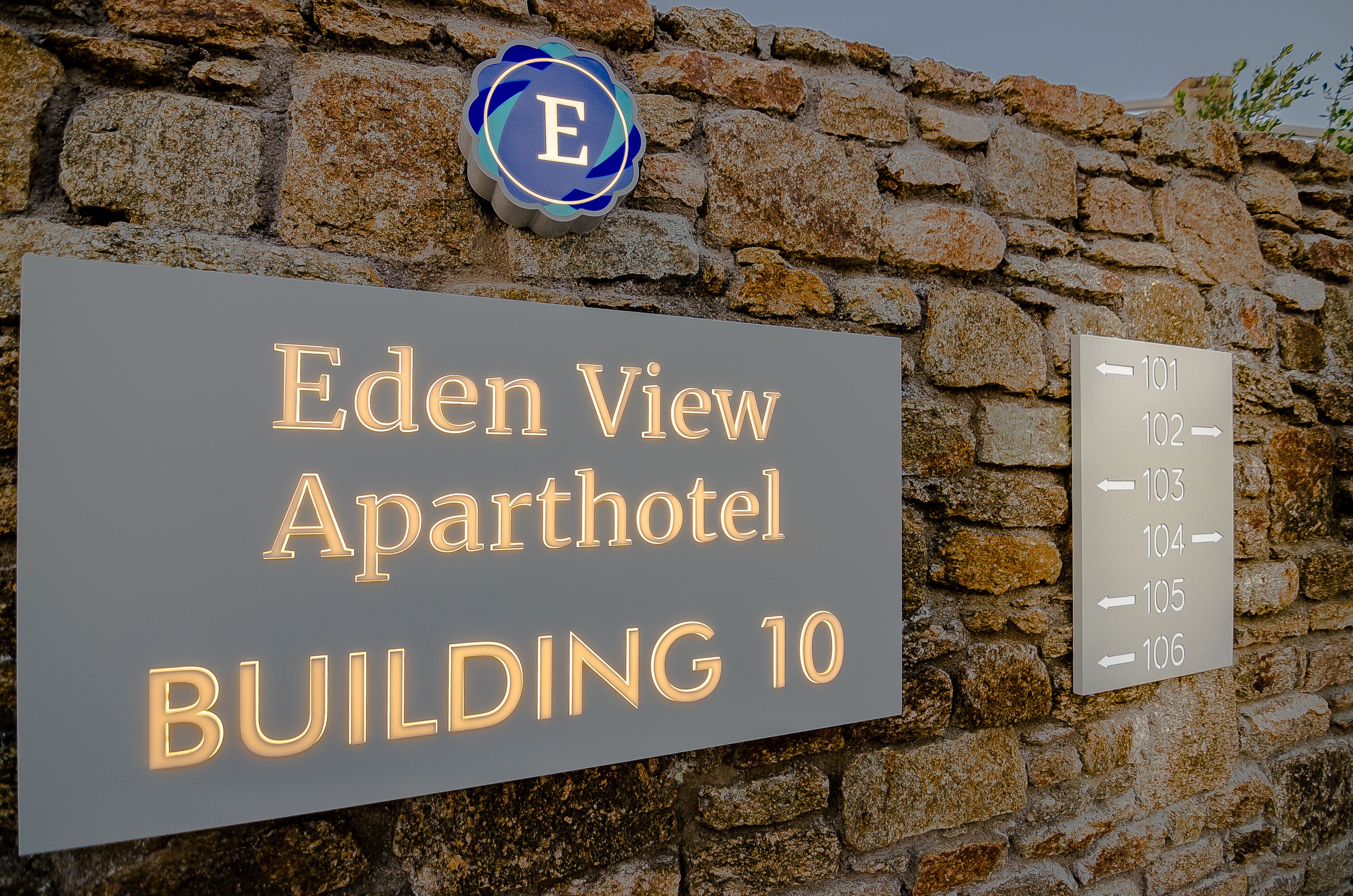 Un panneau indiquant l’« Eden View Aparthotel, bâtiment 10 », avec un panneau directionnel indiquant les numéros de chambre 101 à 106.