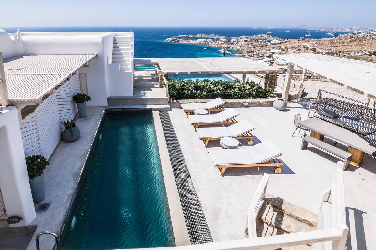 A rooftop pool area with lounge chairs and a view of the sea.