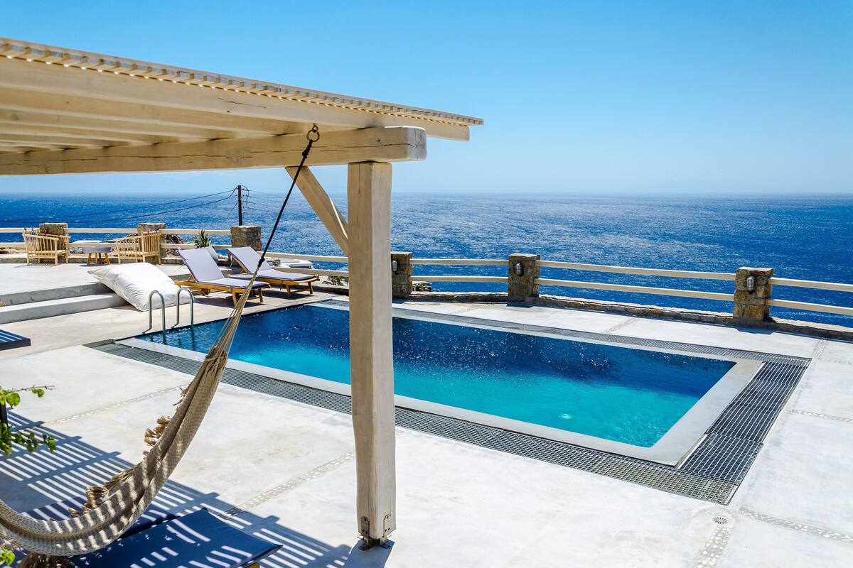 A rooftop pool with clear blue water, surrounded by lounge chairs and a pergola.