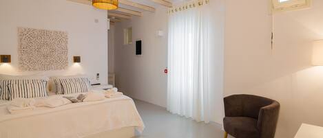 Un dormitorio con una cama, una silla, un candelabro colgante y una ventana con cortinas.