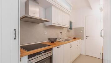 A modern kitchen with white cabinetry, a built-in oven, and a stainless steel range hood.