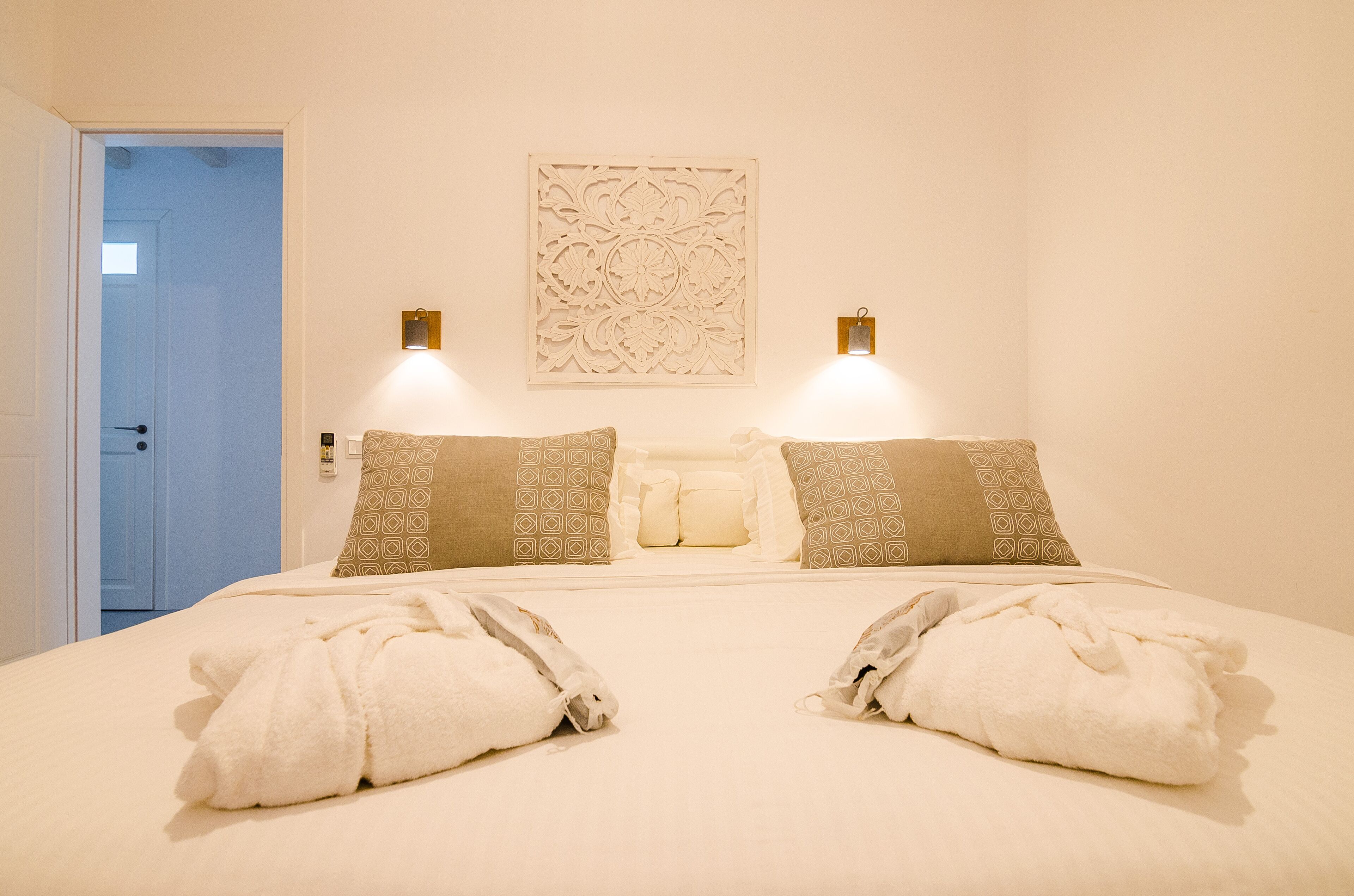 Una habitación de hotel con una cama grande, dos lámparas de noche, almohadas estampadas y un adorno de pared.