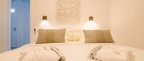 Una habitación de hotel con una cama grande, dos lámparas de noche, almohadas estampadas y un adorno de pared.