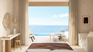 A bedroom with a large bed, a desk, and a chair, with a view of the sea and a balcony. - Eden View Suites & Villas (Mykonos)