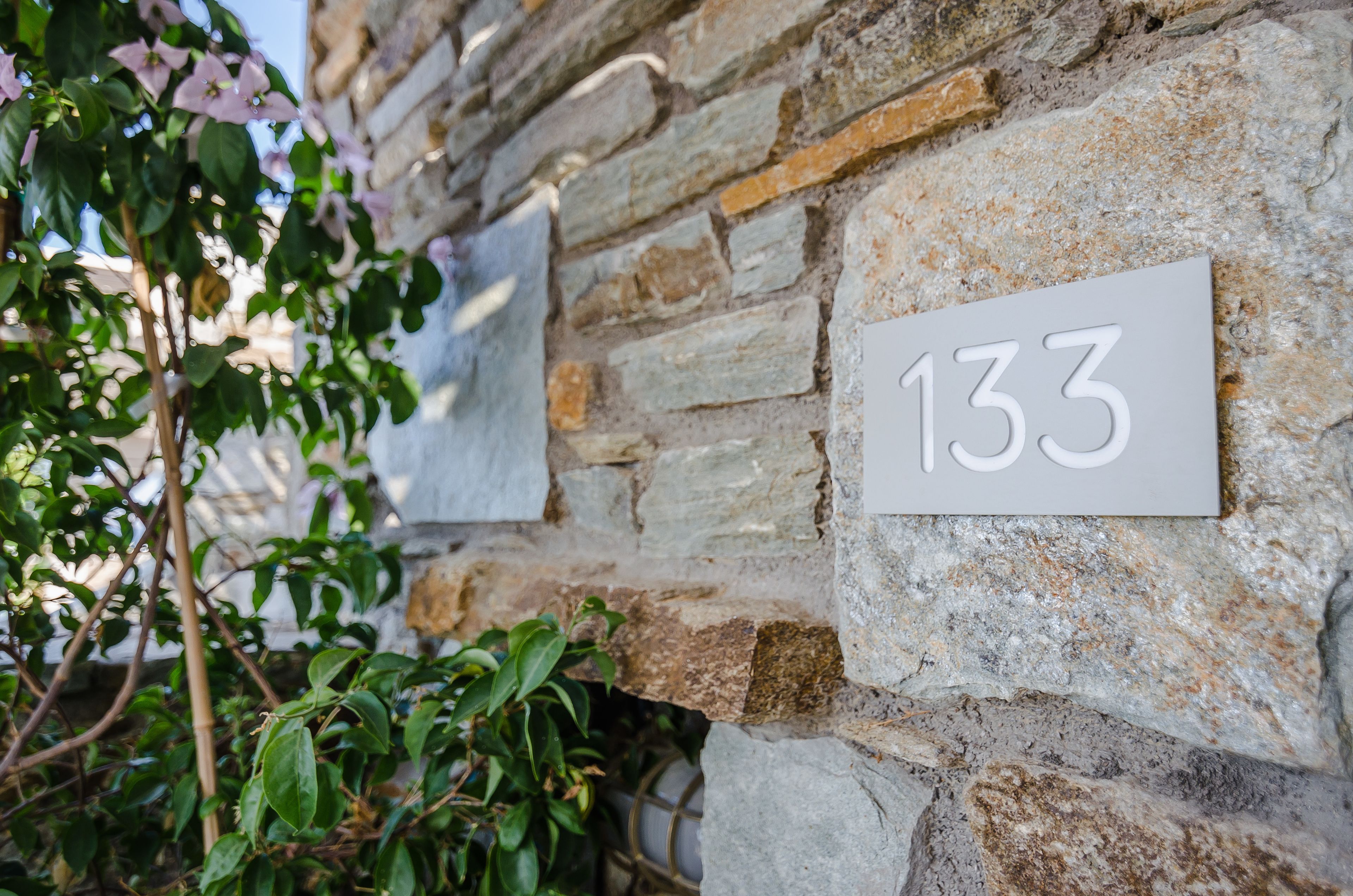 A stone wall with a sign displaying the number 133.