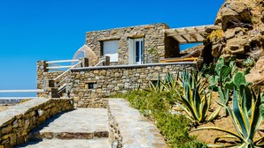 A stone building with a staircase leading to a balcony overlooking a rocky landscape. - Eden View Suites & Villas (Mykonos)