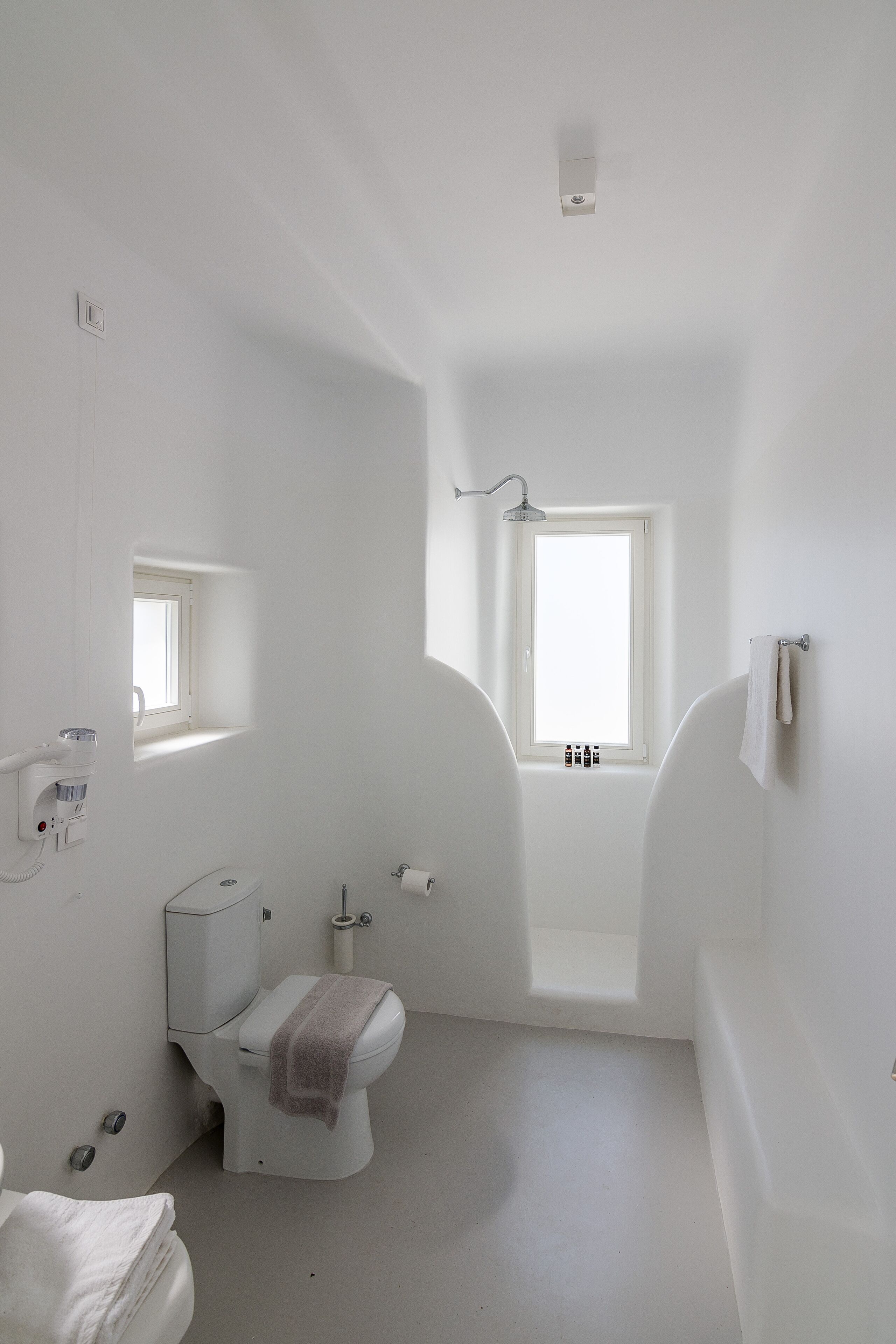 A small, white bathroom with a toilet, a bathtub, and a window.