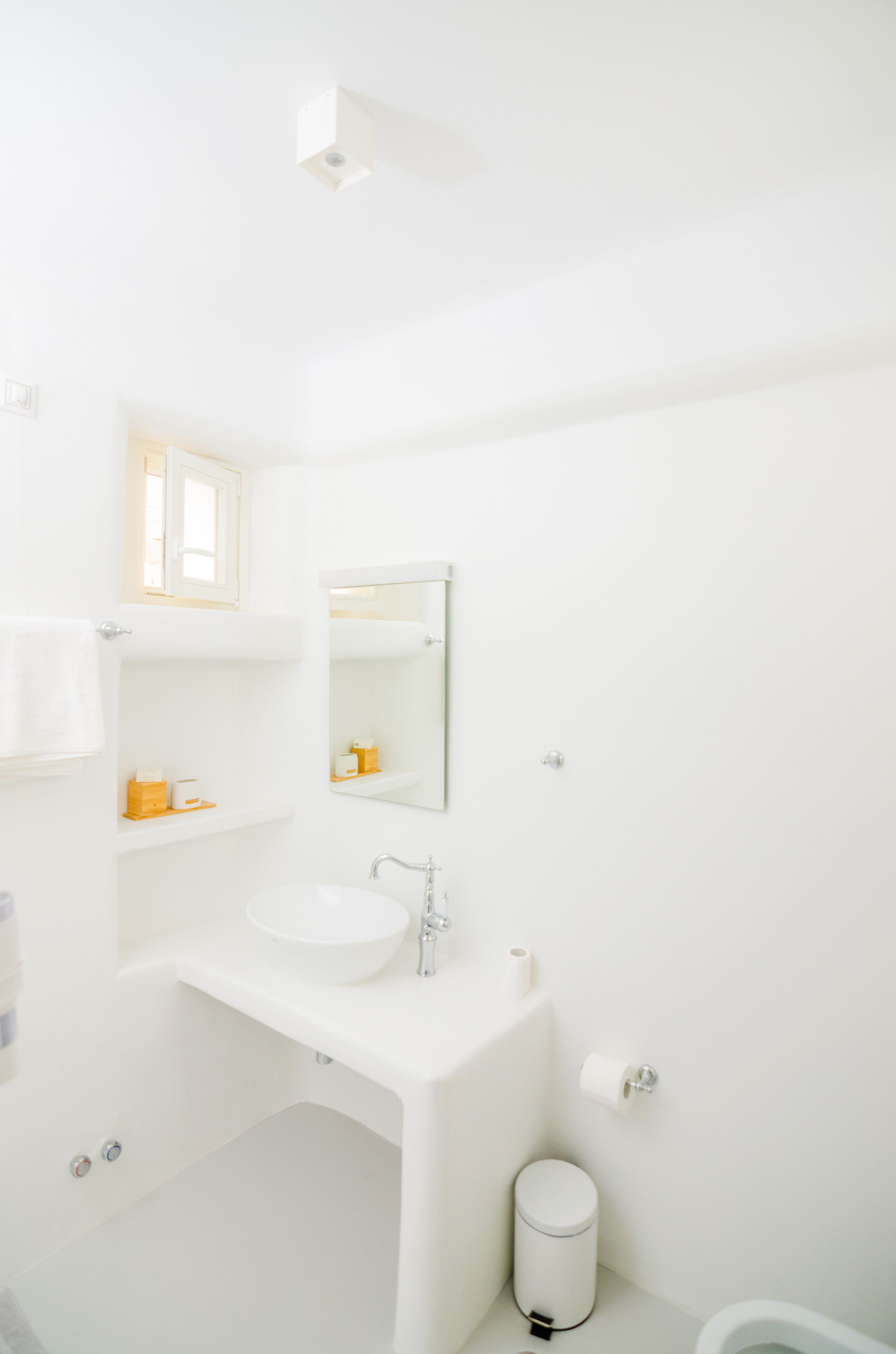 A white bathroom with a sink, mirror, and toilet.