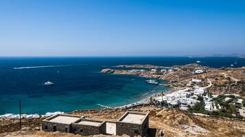 Un pueblo costero con edificios blancos, un paisaje rocoso y barcos en el mar.