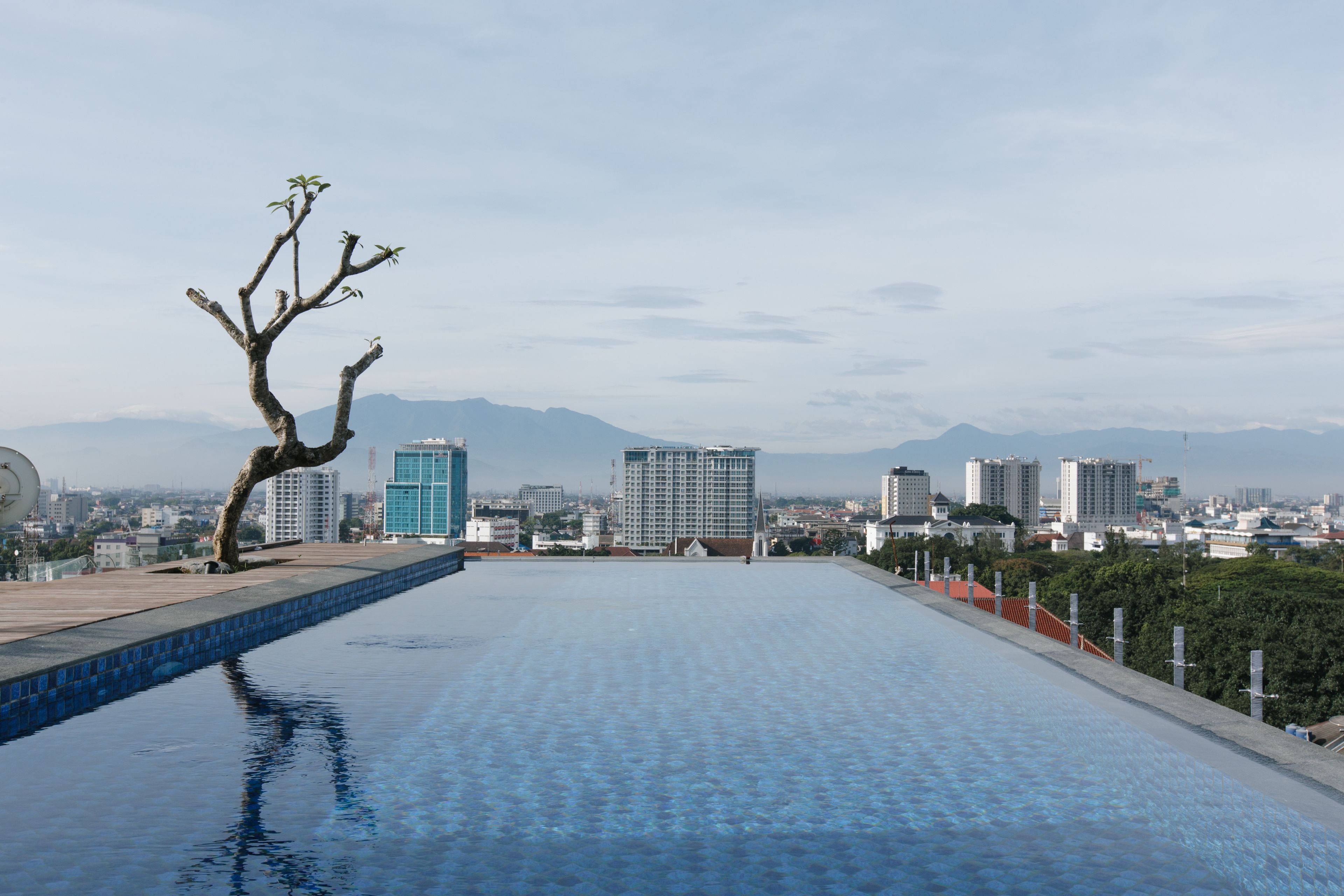 A rooftop pool with a view of a cityscape and mountains in the distance.