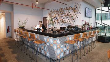 A bar area with a patterned counter, bar stools, and a person standing behind it.
