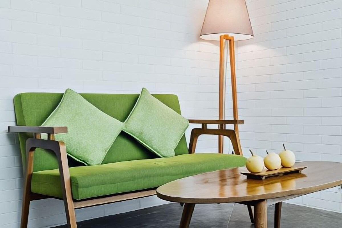 A green sofa with wooden legs and a wooden side table with pears.