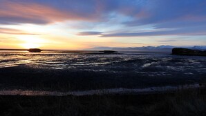A sunset over a flat landscape with distant mountains. - Hvammur Apartments (Höfn)