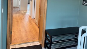 A hallway with wooden flooring, a bench, and a sign on the wall. - Hvammur Apartments (Höfn)