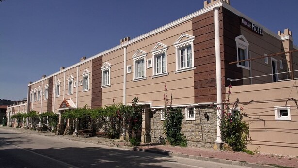 A hotel with a symmetrical facade, multiple windows, and a stone base.