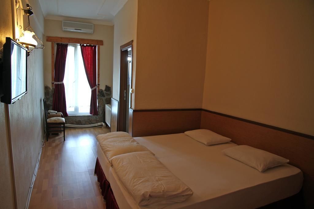 Una habitación de hotel con una cama grande, un escritorio, una silla y una ventana con cortinas.