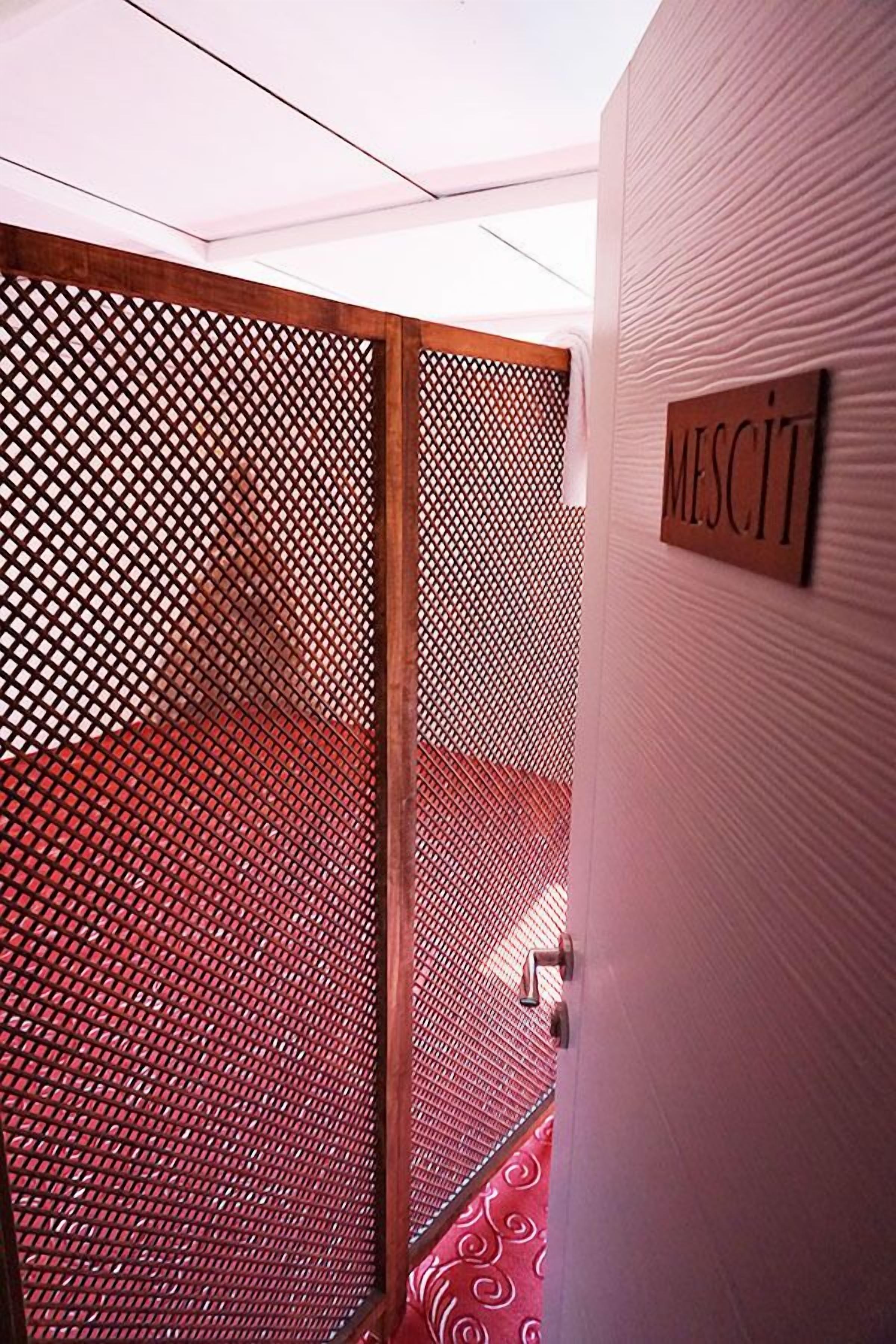 Una habitación con un separador de madera lattice, alfombra roja con diseño y un cartel que dice 'MISCELLANEOUS'.
