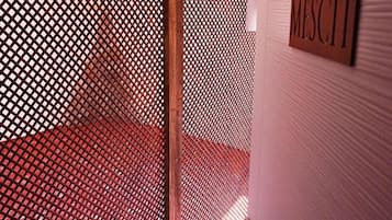 Una habitación con un separador de madera lattice, alfombra roja con diseño y un cartel que dice 'MISCELLANEOUS'.