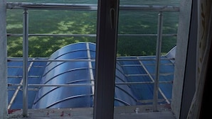 A view from a window with a metal railing, overlooking a body of water and a distant shoreline.