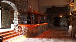 A stone-walled bar area with a wooden counter, steps leading up to it, and a patterned floor.