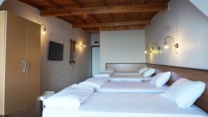 A hotel room with a wooden ceiling, a large wardrobe, and a bed with white linens.