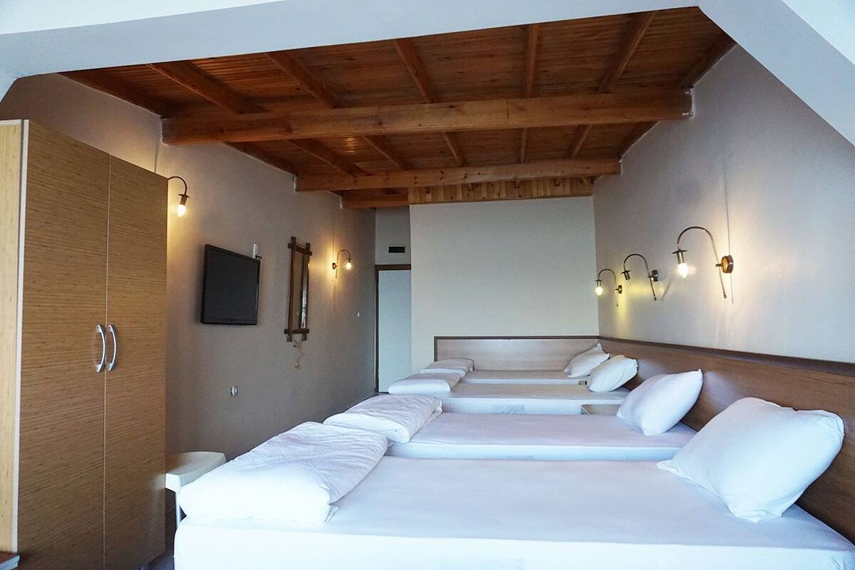 A hotel room with a wooden ceiling, a large wardrobe, and a bed with white linens.
