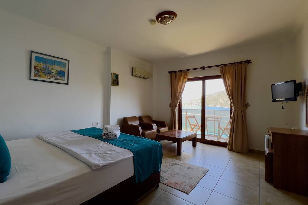 Une chambre d’hôtel équipée d’un lit, d’un bureau, d’une chaise, d’une télévision et offrant une vue sur la mer.