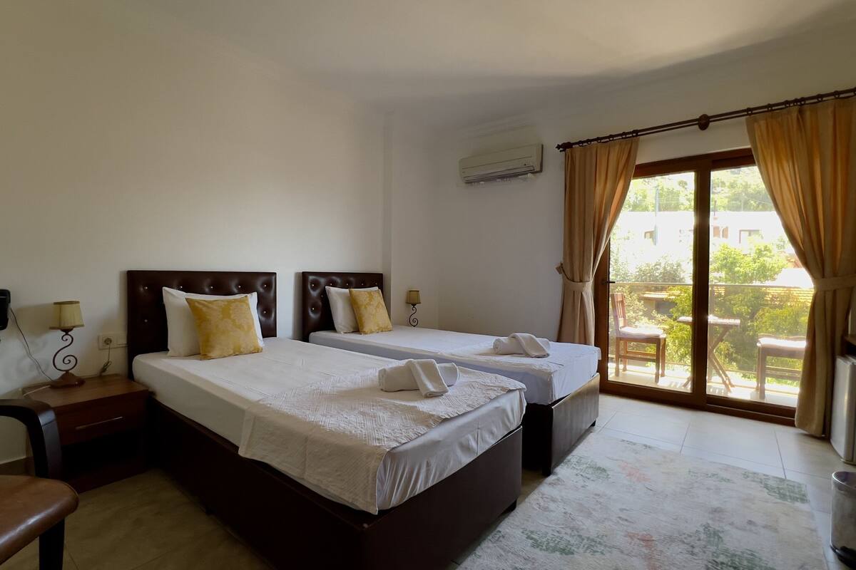 Une chambre d’hôtel avec deux lits, une chaise, un bureau, un téléphone et une télévision.