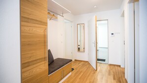 Ein modernes Schlafzimmer mit einem Holzschrank, einer Bank und einem Spiegel.