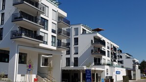 Ein modernes Mehrfamilienhaus mit Balkonen, blauem Himmel und einem Verbotsschild für Fahrzeuge.