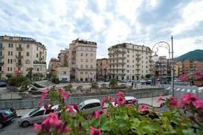 A cityscape with multi-story buildings, a pedestrian area with benches, and cars parked along the street. - B&B Antonello (Salerno)