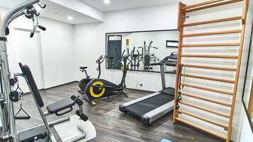 Un gimnasio con equipo de ejercicio, incluyendo una cinta de correr, bicicleta estática y máquinas de pesas.