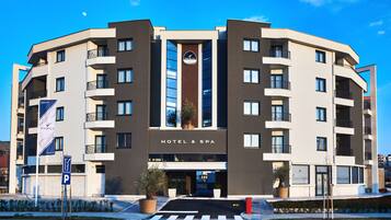 A modern hotel with a central entrance, balconies, and a sign indicating it is a hotel and spa.