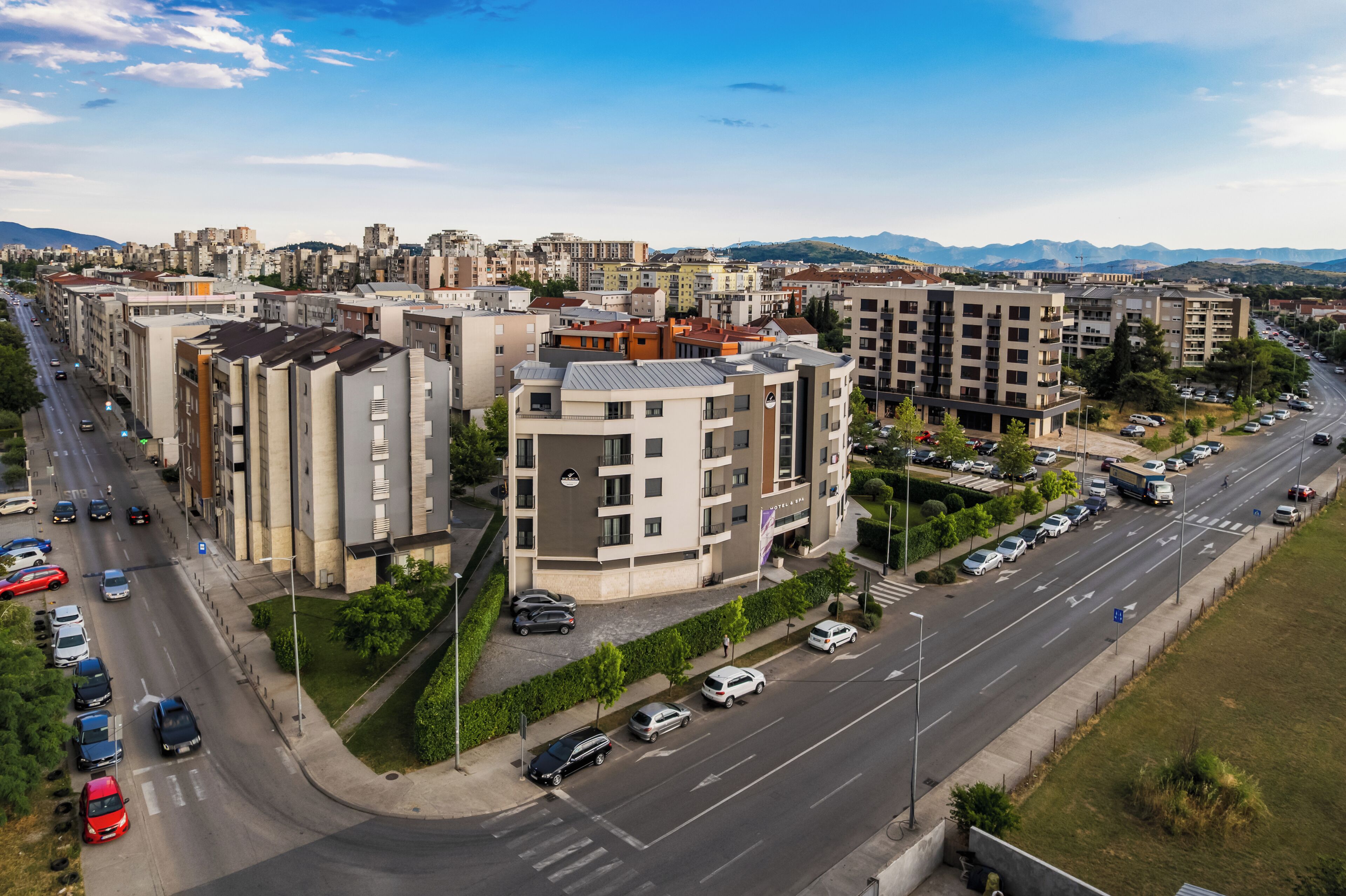 An urban landscape with multi-story residential buildings, a main road, and a parking area.