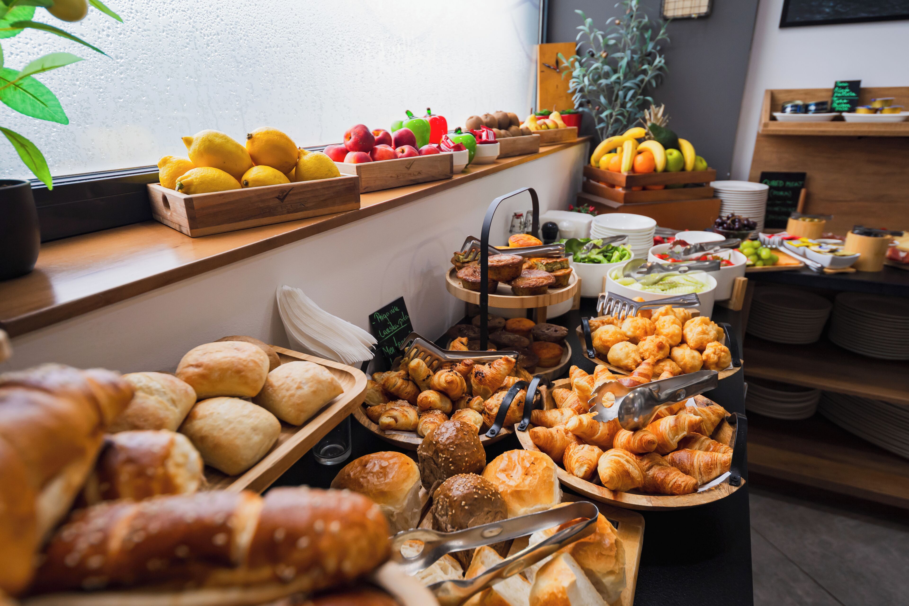 Un buffet de petit-déjeuner proposant une variété de pains, de viennoiseries, de fruits et de légumes.