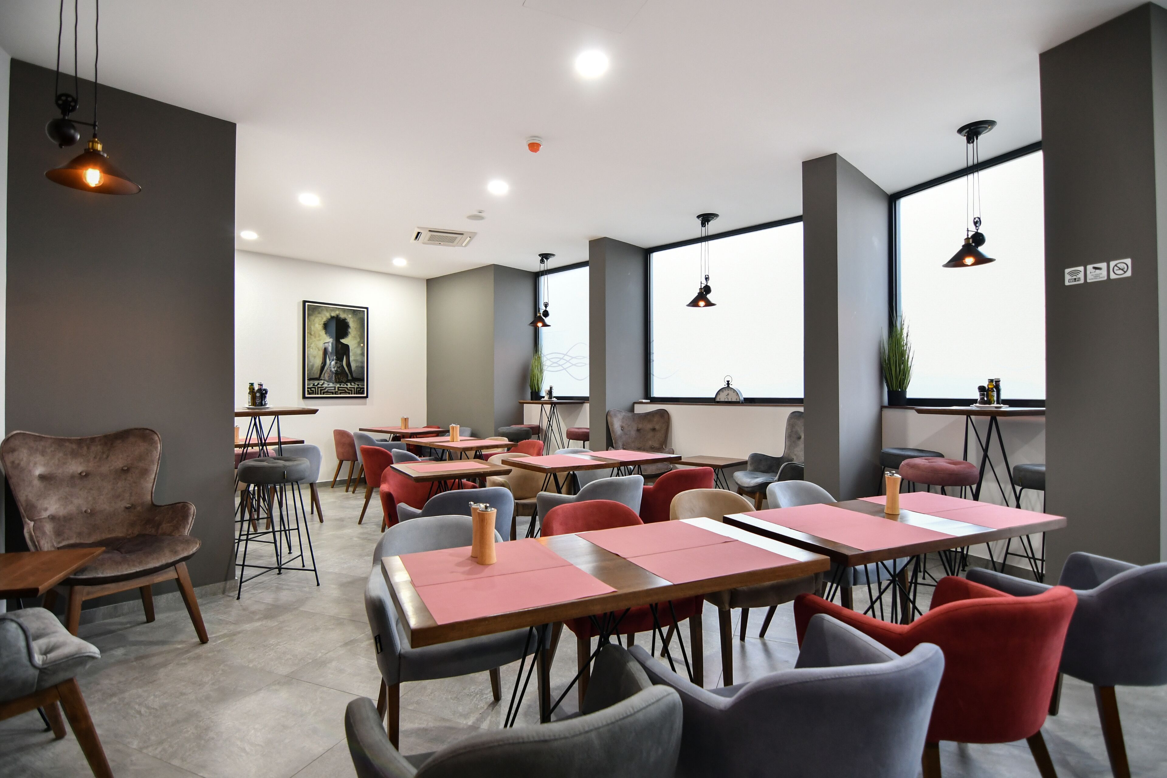 A modern conference room with tables and chairs, large windows, and pendant lighting.