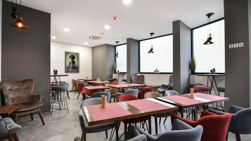 A modern conference room with tables and chairs, large windows, and pendant lighting.