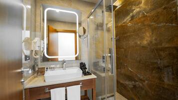 A modern bathroom with a glass shower enclosure, a wooden vanity, and a large mirror.