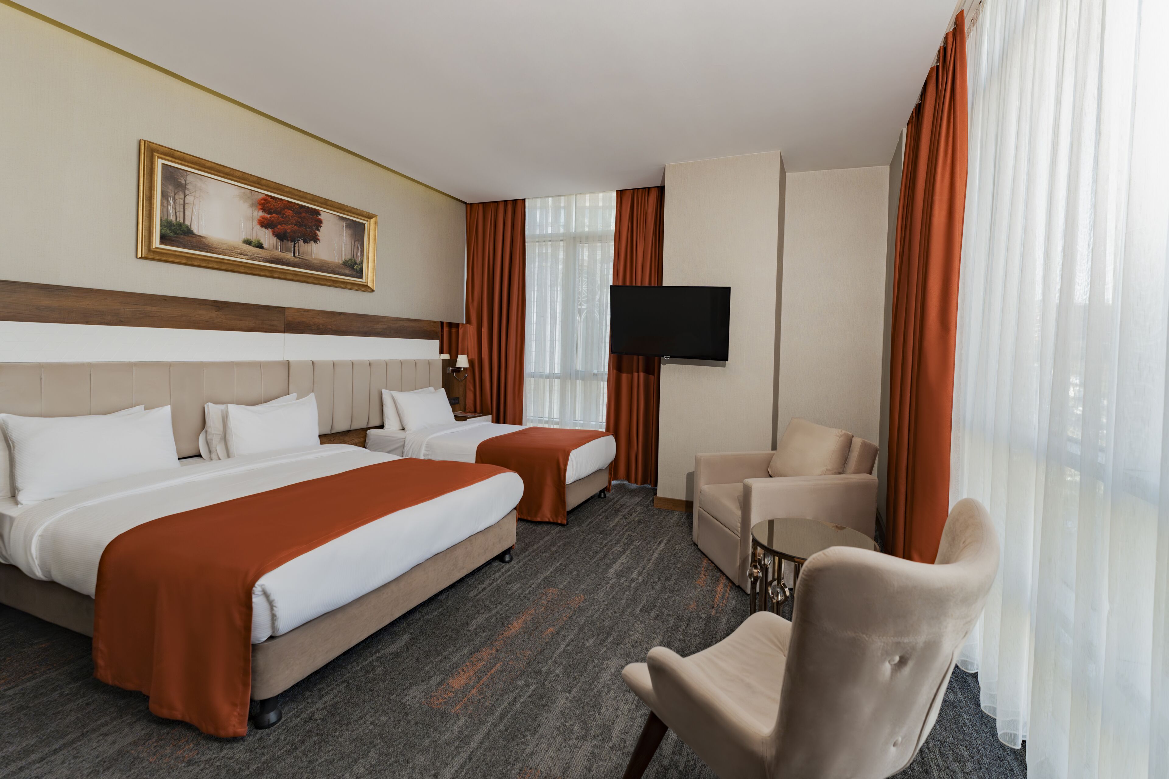 A hotel room with two beds, a TV, a sofa, and a painting on the wall.