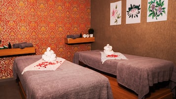 Relax in a serene spa room with two massage tables, adorned with decorative swans and surrounded by vibrant artwork.