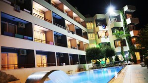 A multi-story hotel with balconies, a swimming pool, and outdoor lighting. - Side Kervan Hotel (Manavgat)