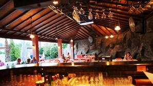 An outdoor bar area with a rustic stone wall, wooden ceiling beams, and a pool table. - Side Kervan Hotel (Manavgat)