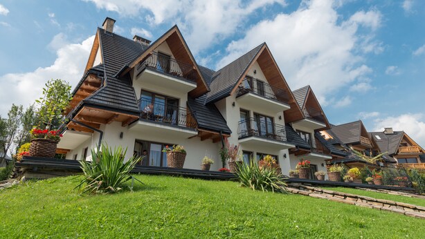 Ein modernes, zweistöckiges Haus mit geneigtem Dach, großen Fenstern und einem Balkon.