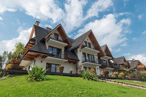 A modern two-story house with a sloped roof, large windows, and a balcony. - Janówka Apartamenty (Koscielisko)