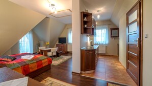 Ein Schlafzimmer mit einem Bett, einem Schreibtisch, einem Stuhl und einer Küchenzeile.