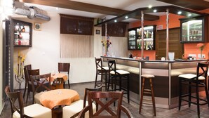 Ein Restaurant mit Barbereich, verschiedenen Sitzmöglichkeiten, darunter runde Tische und Barhocker, sowie einer Auswahl an Getränken auf Regalen.